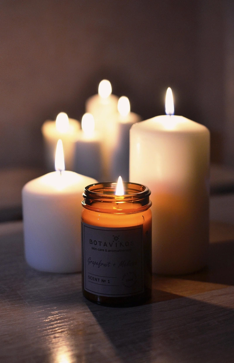Lit pillar candles surrounding a candle in an amber glass jar